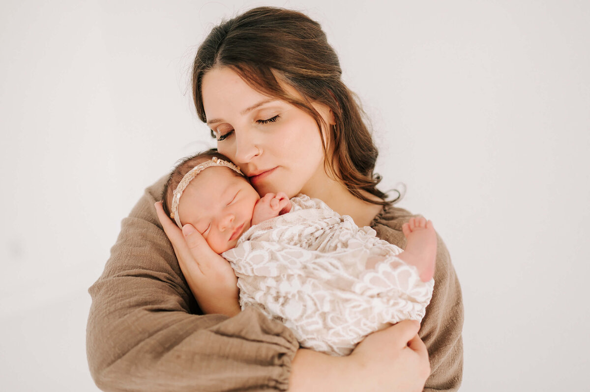 mom cuddling newborn baby girl in swaddle during Springfield Mo newborn photgraphy session