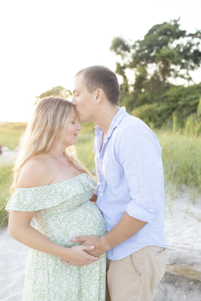 mom and dad pose during maternity portraits on the beach