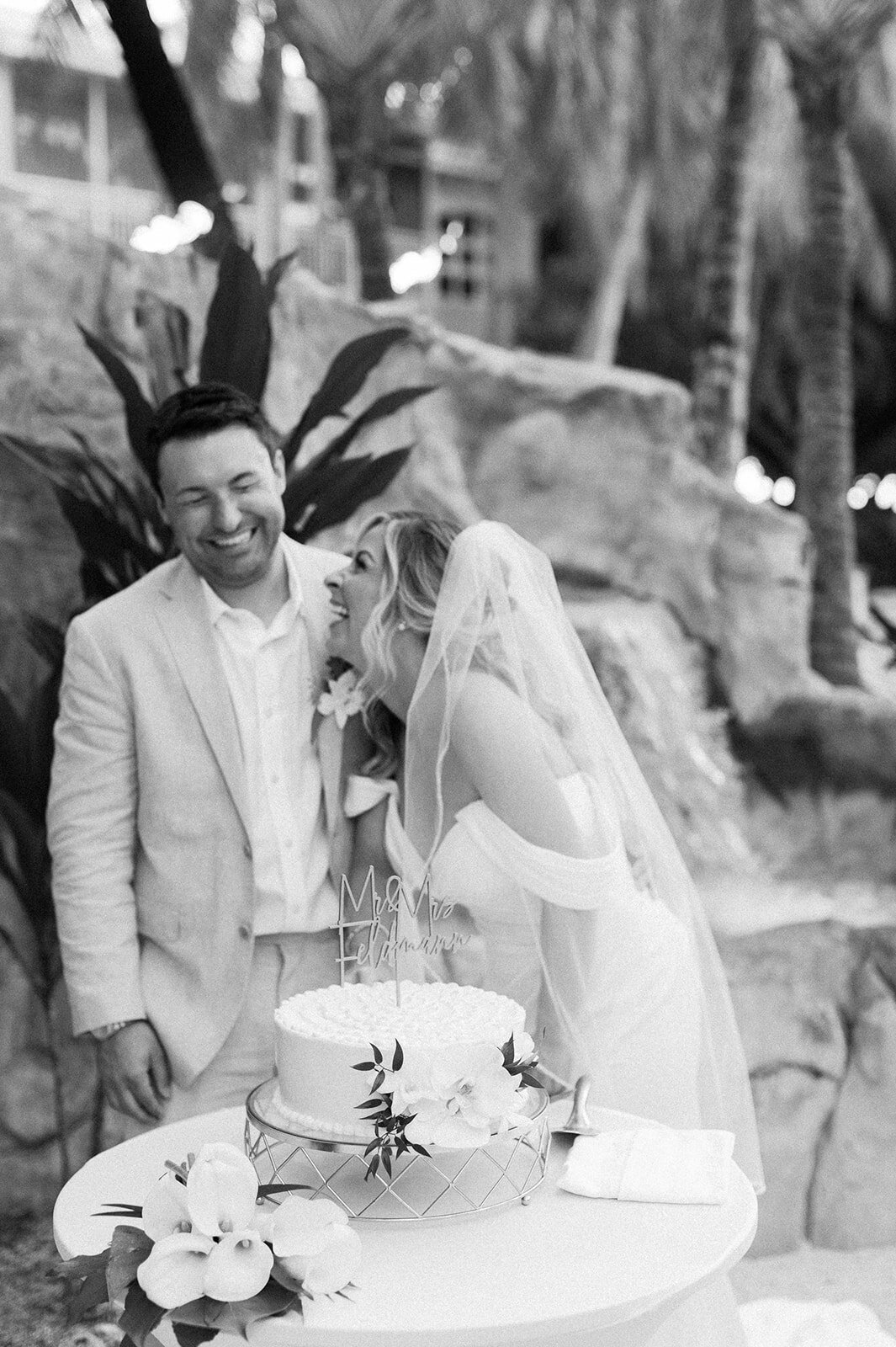  Monica enjoys a lighthearted cake-cutting moment with Austyn during their destination wedding celebration.