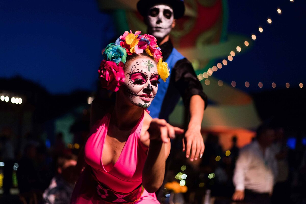 A dancer with Day of the Dead face paint entertains guests during an outdoor dinner performance