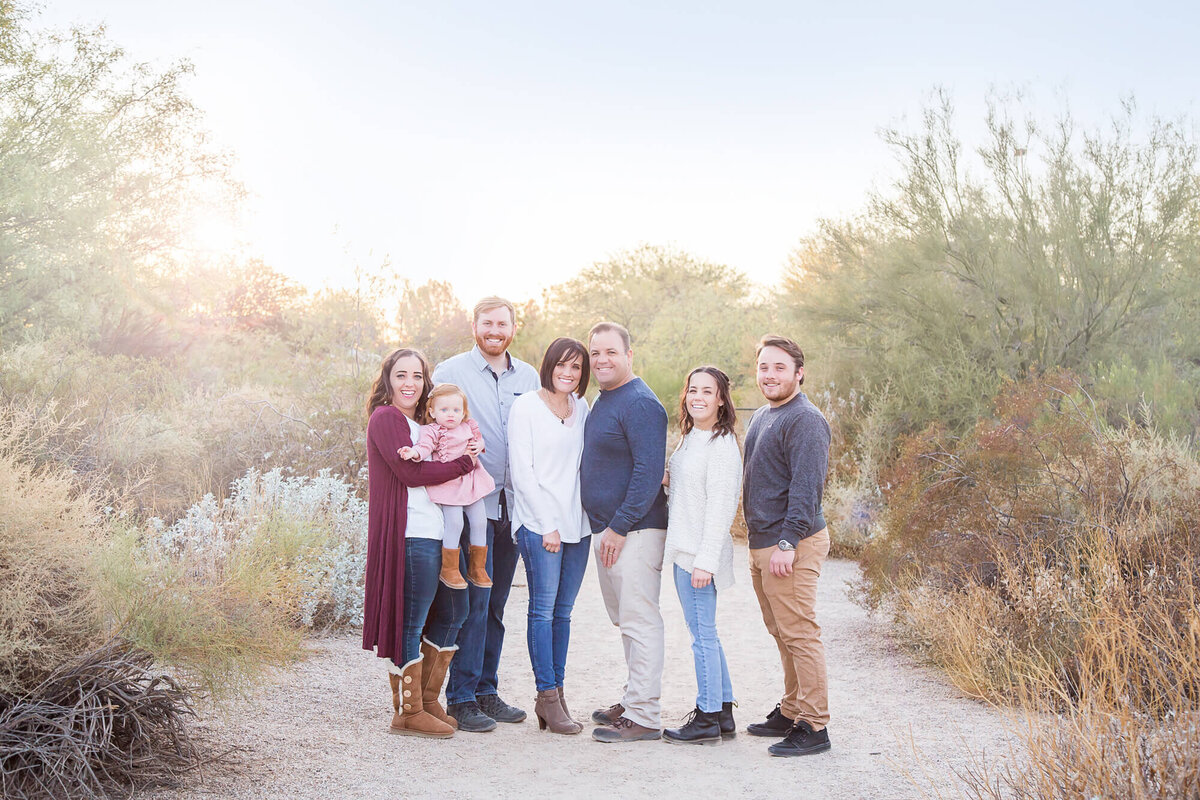 portrait of family standing on a desert park path with glowing sunset behind