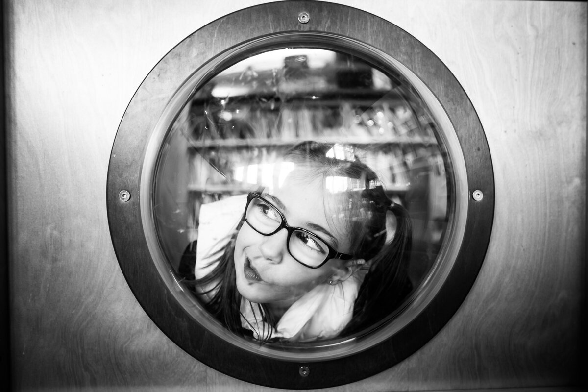 girl looking through window with glasses on