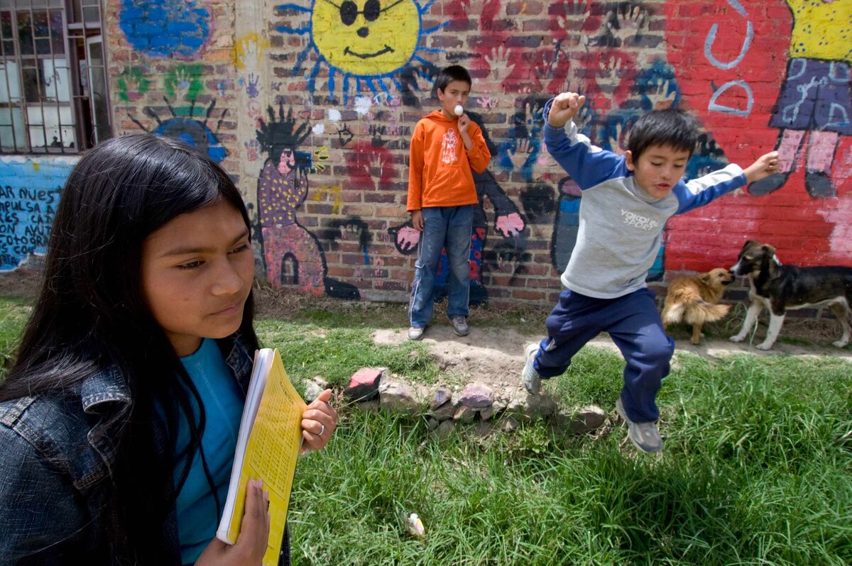 Children jump and play outside wall with colorful paint. Scenes from a Shanty Town in Columbia