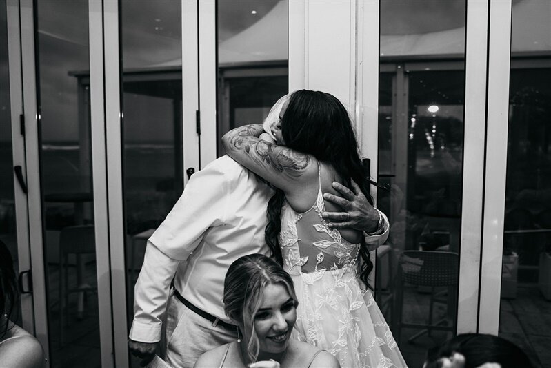 "Capture the heartwarming moment of Tamara embracing her father amidst the joyous ambiance of the wedding reception. A tender embrace filled with love and cherished memories. Discover more heartfelt moments captured at this unforgettable celebration."