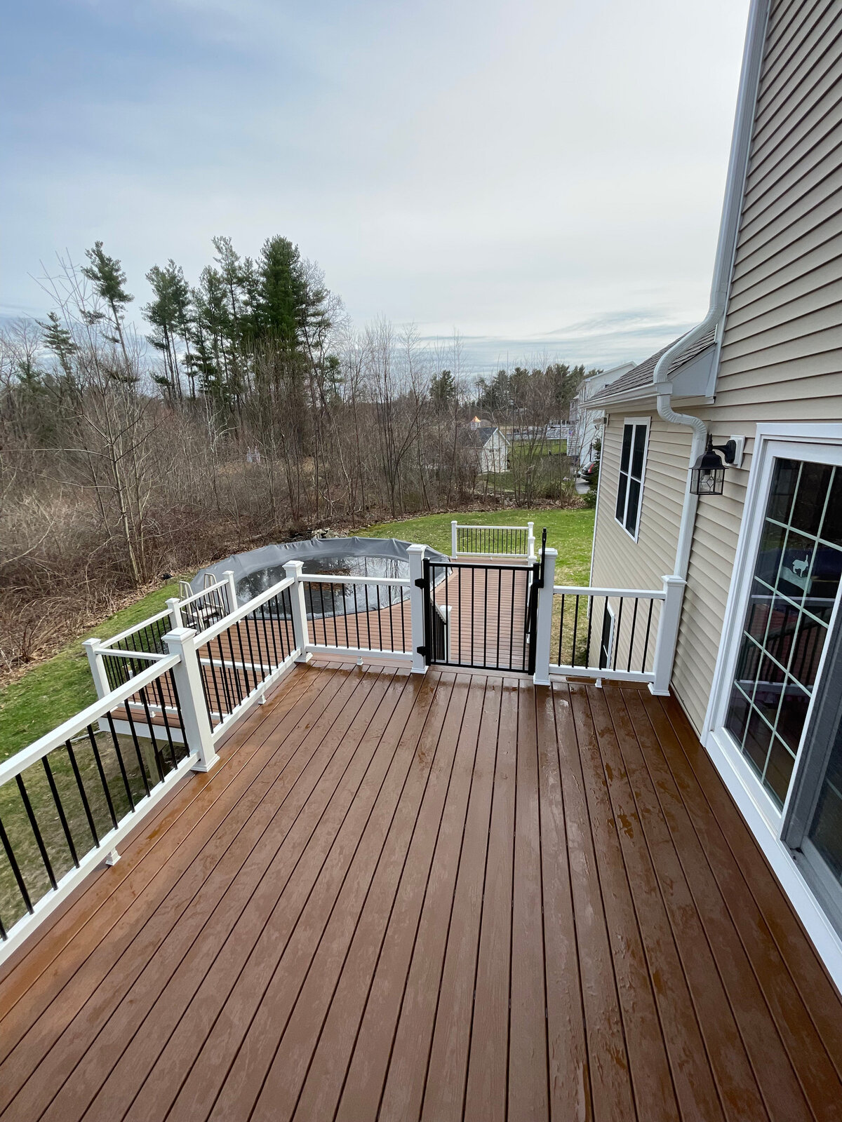 A look from above of a two tier deck built with composite and PVC railings with a child safety gate on the stairs