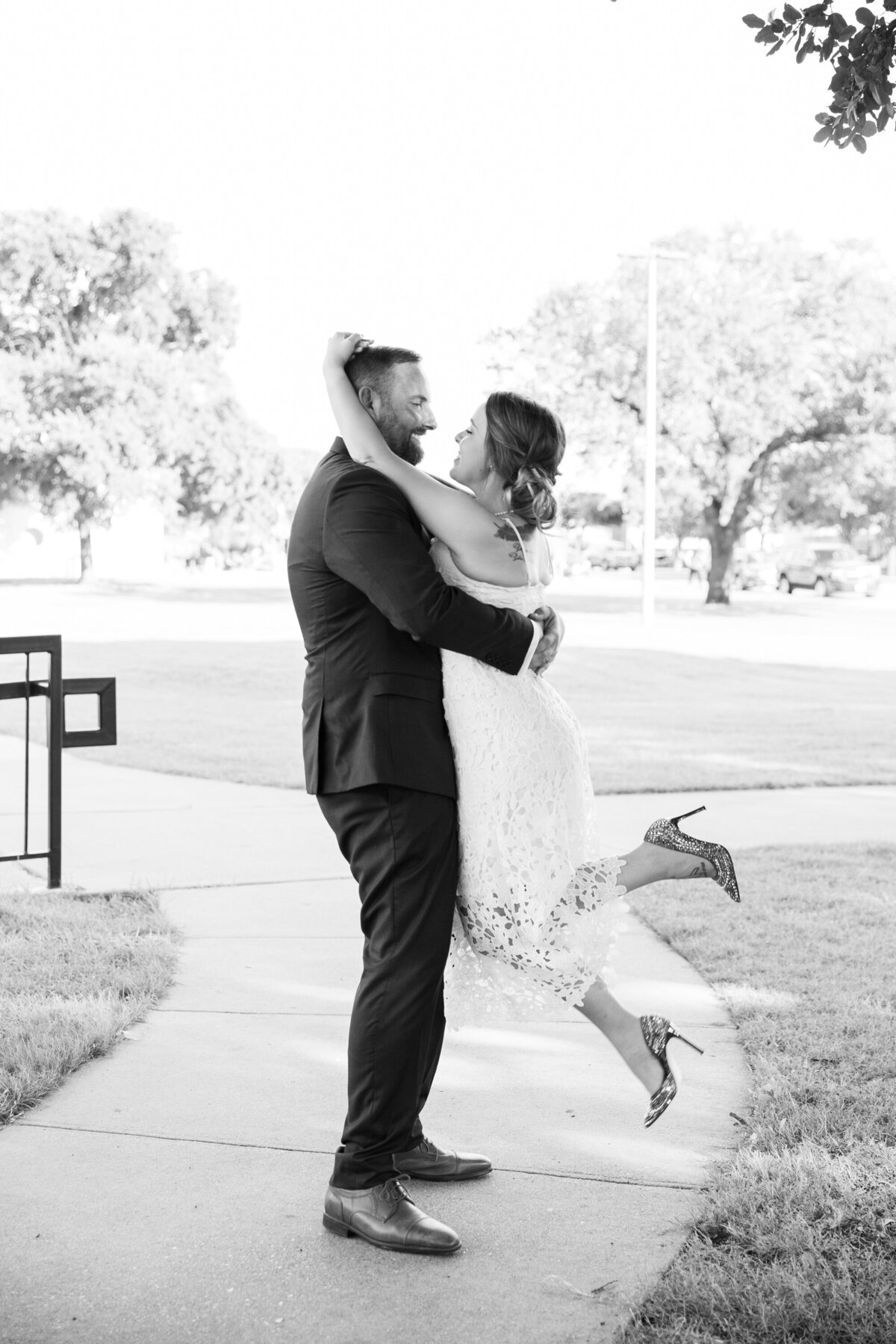 A bride and groom passionately hugging in front of a beautiful park captured by an Austin wedding photographer.
