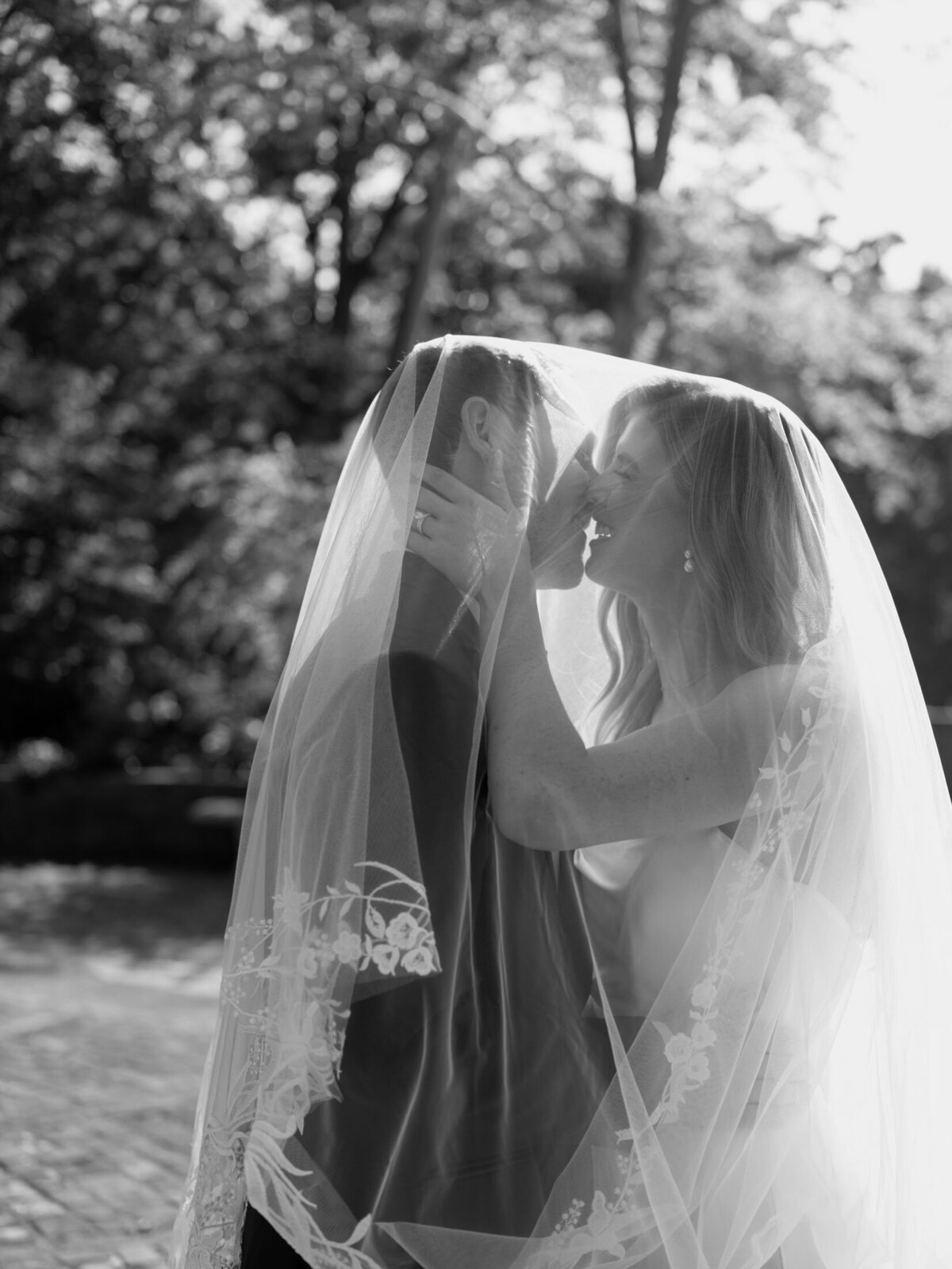 Bride and groom kissing under the veil at Italian Cultural Gardens in Cleveland