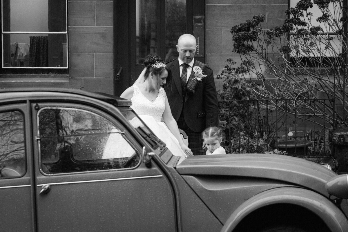 a couple and their daughter look at an old Citroen 
