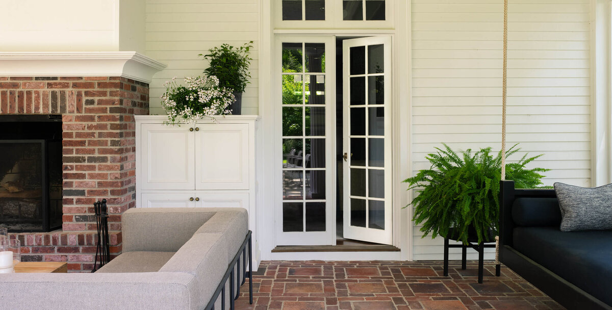 Historic home design in Boston featuring original red brick flooring on a covered porch with traditional architecture and modern furniture.