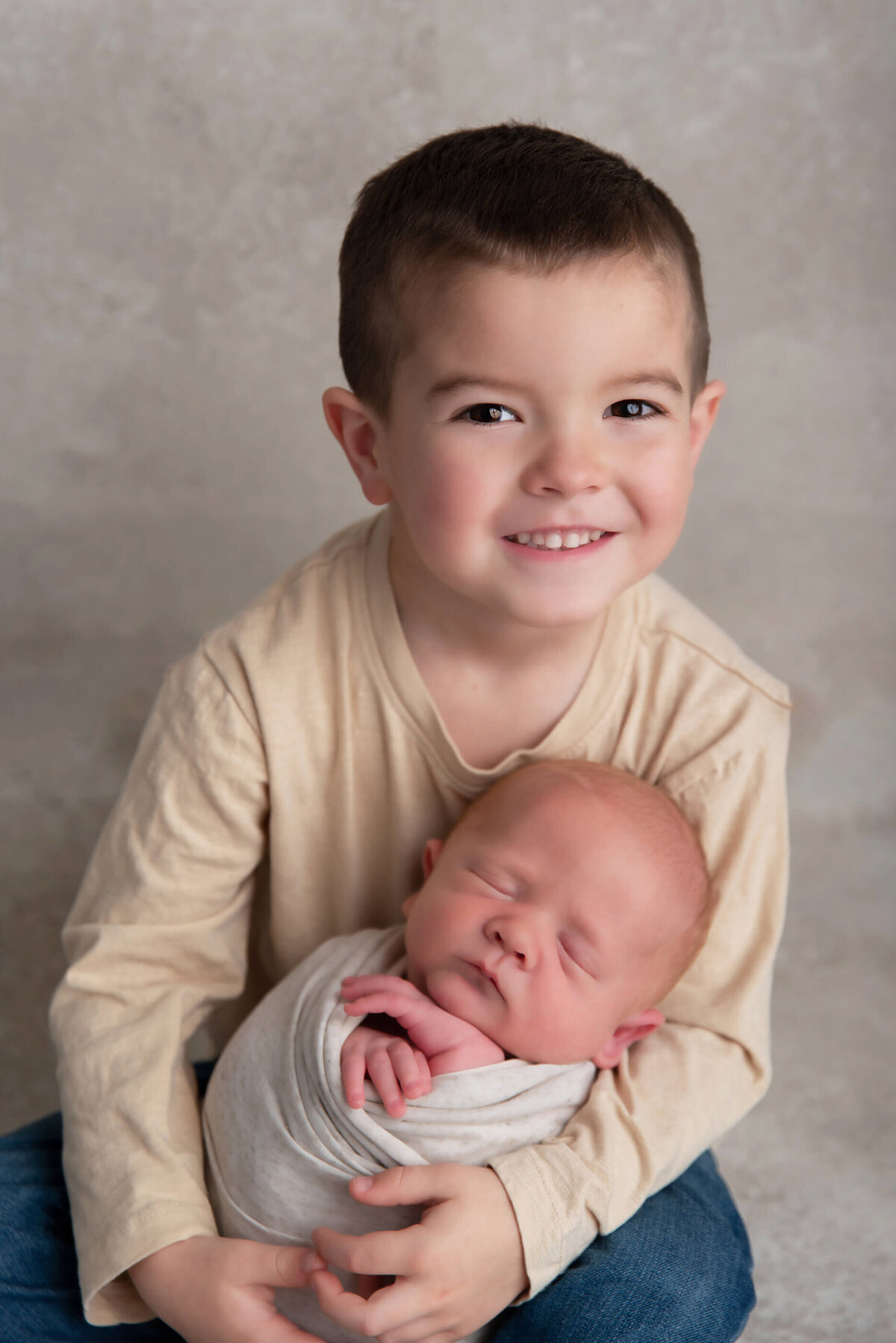 Big brother holding newborn brother for their newborn photos