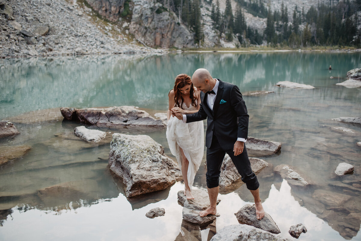 Jackson Hole Photographers capture groom helping bride walk after Grand Teton elopement