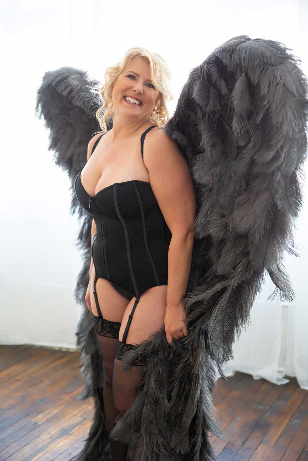 Milestone-boudoir-for-older-woman-wearing-grey-angel-wings-in-black-lingerie
