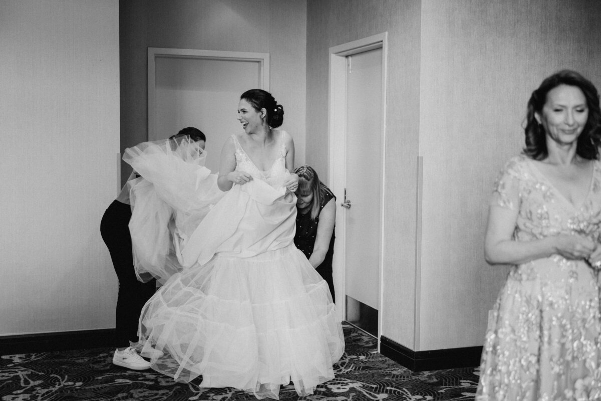 A bride putting on her wedding dress, helped by her family and bridesmaid
