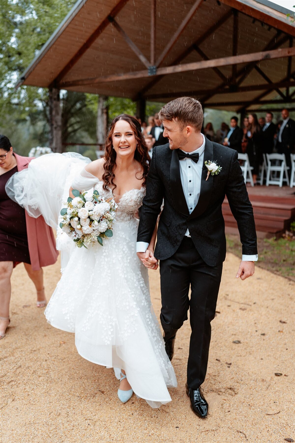 The newlyweds share a tender kiss as they exit the ceremony, radiating love and joy in their post-nuptial bliss.