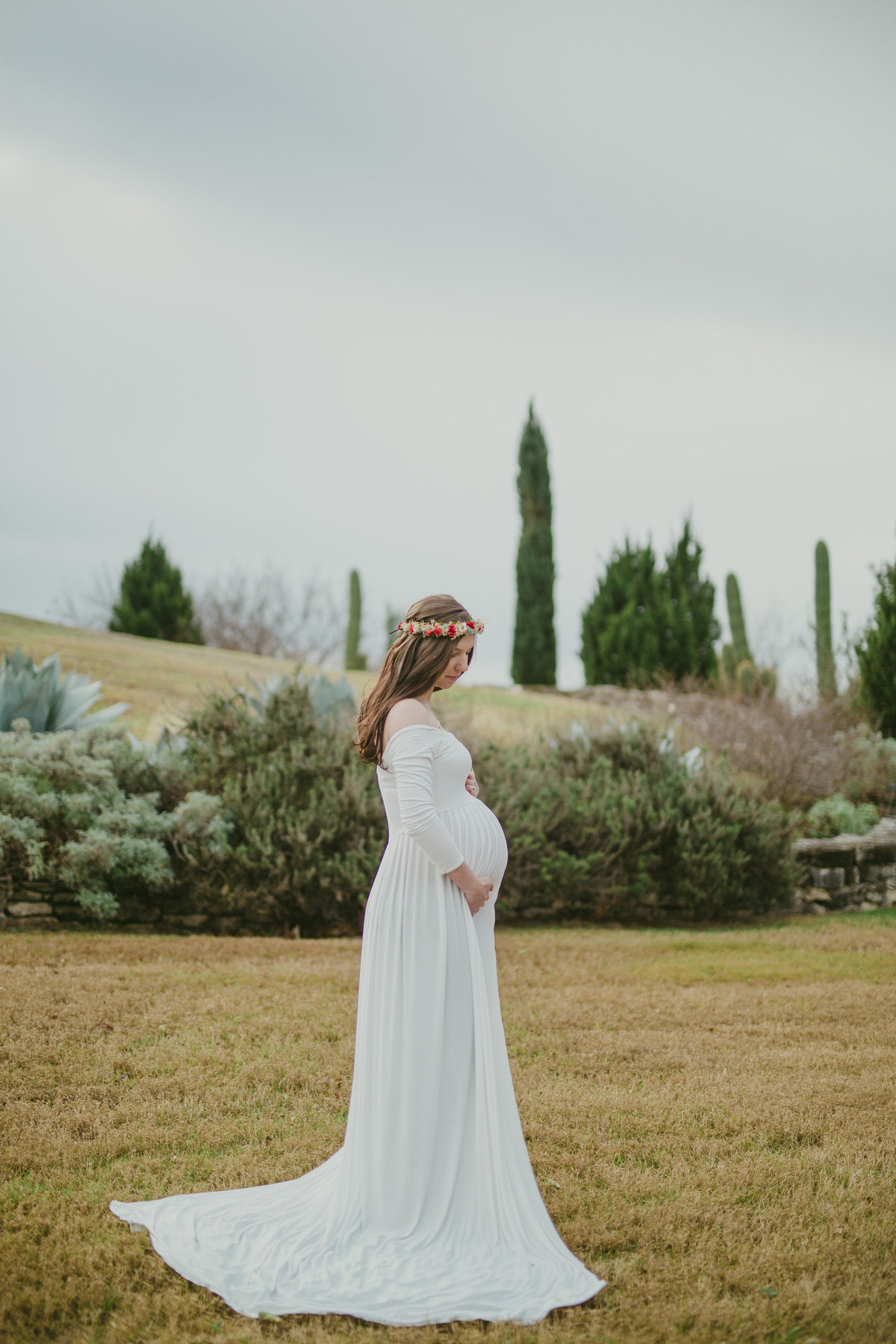woman in a maternity dress wearing flower crown for her maternity photography session at San Antonio Botanical Garden.