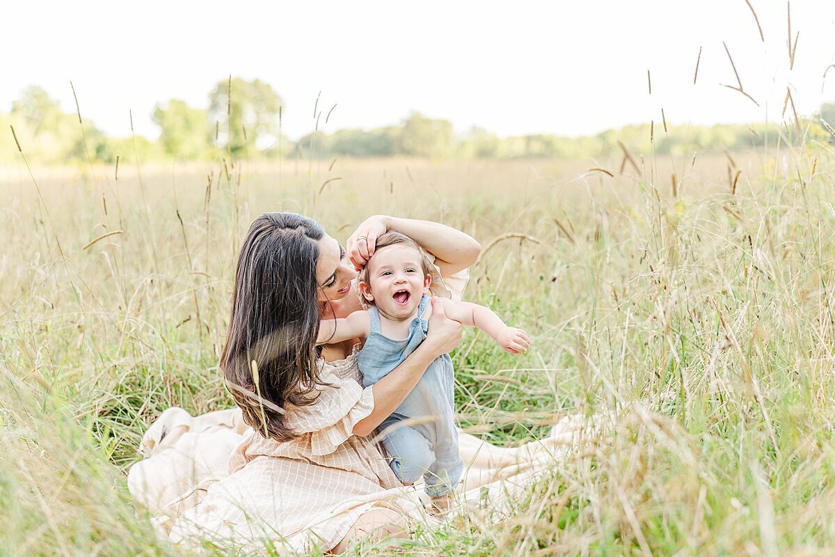 Mother sits in field with son during Family photo session with Sara Sniderman Photography at Heard Farm in Wayland Massachusetts
