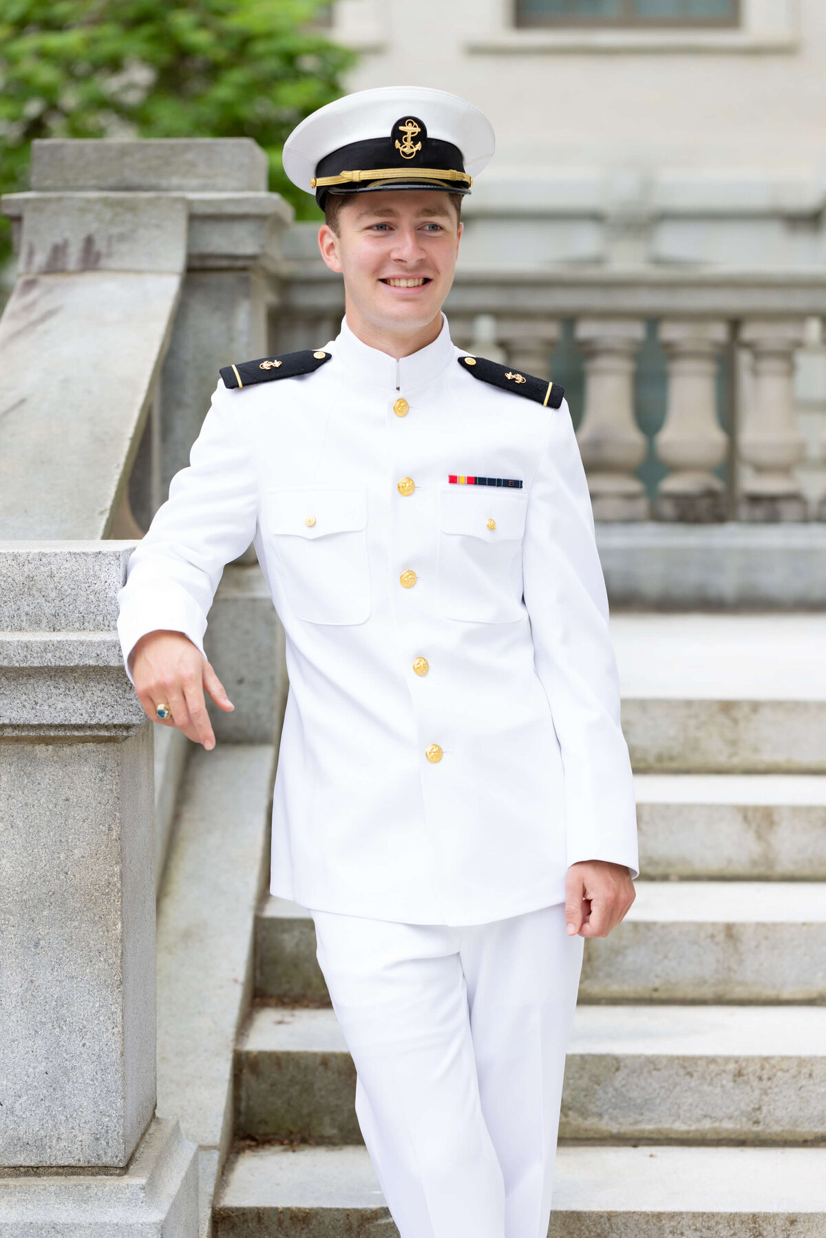 Naval Academy graduate senior portrait in white uniform at Mahan Hall.