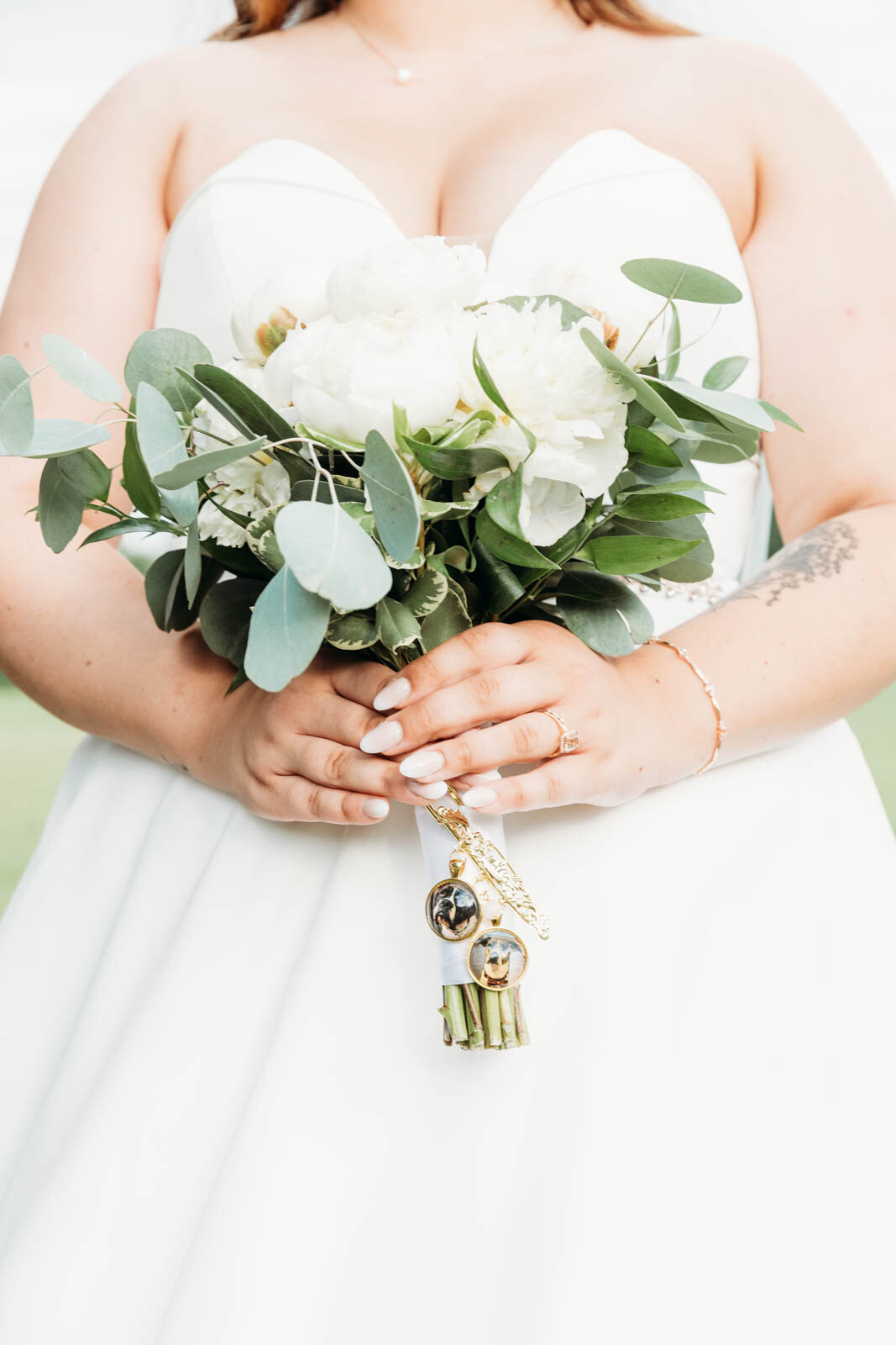 Details of a bride's white bouquet with dog lockets