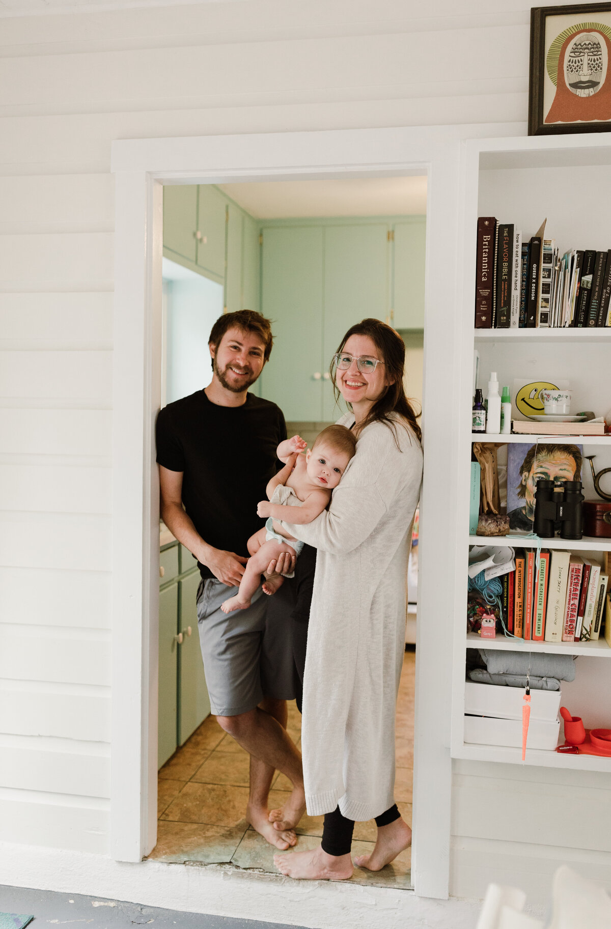 Family photo session in Austin, parents standing in doorway holding baby