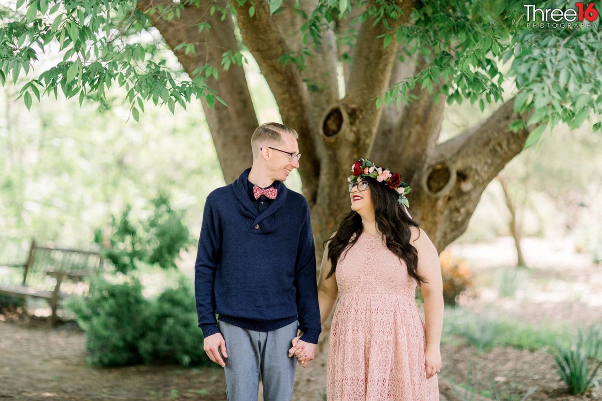 Engaged couple hold hands as they gaze at each other