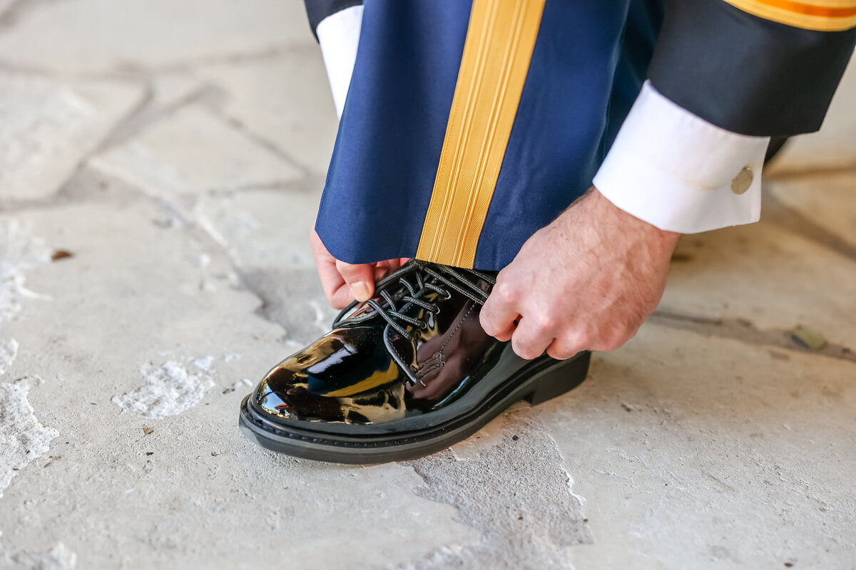 military wedding groom ties shoe in uniform at wedding in Austin Texas