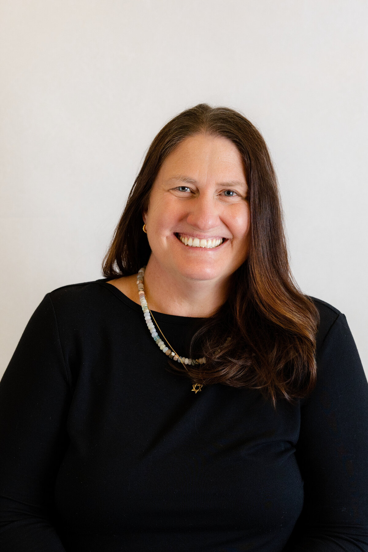 Woman smiling and wearing black and sitting for a professional headshot in the Bay Area