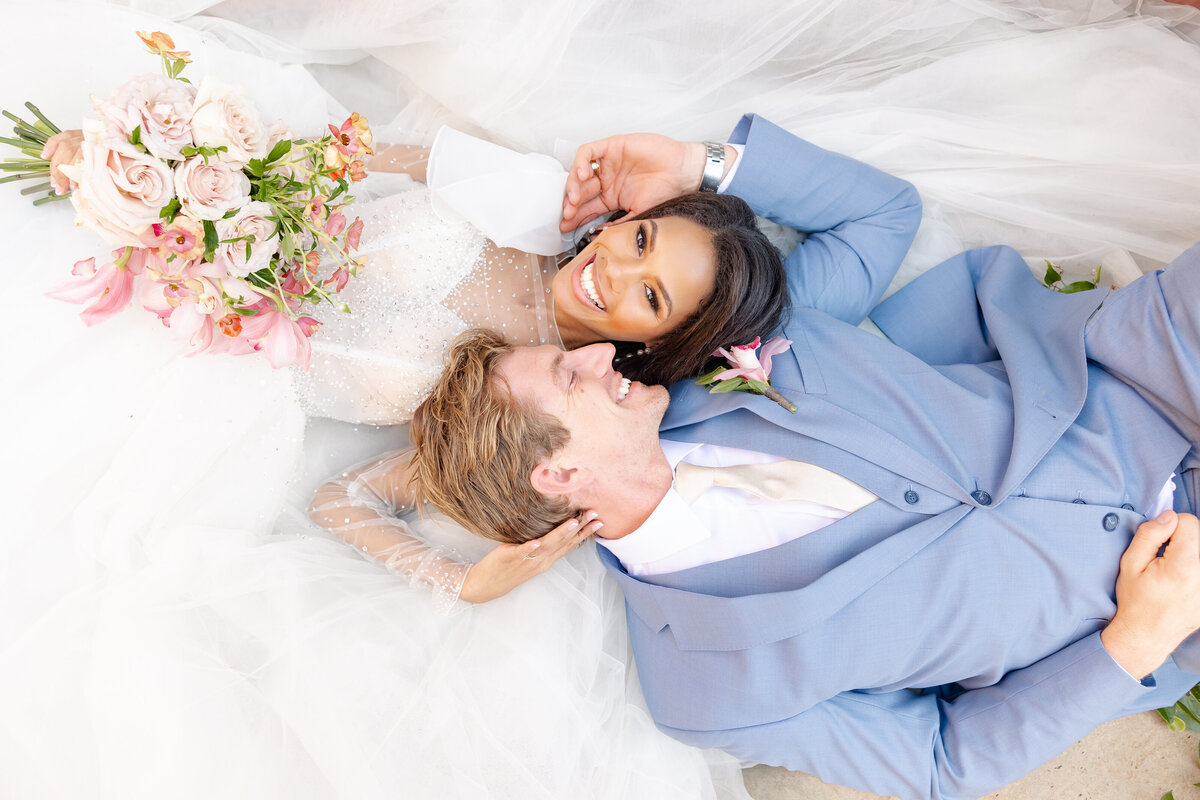 light and airy photo of Charleston wedding couple laying in high end wedding dress and custom tux