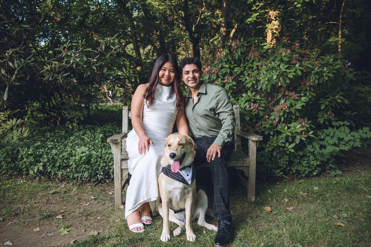 Couple sitting with their dog on a garden bench.