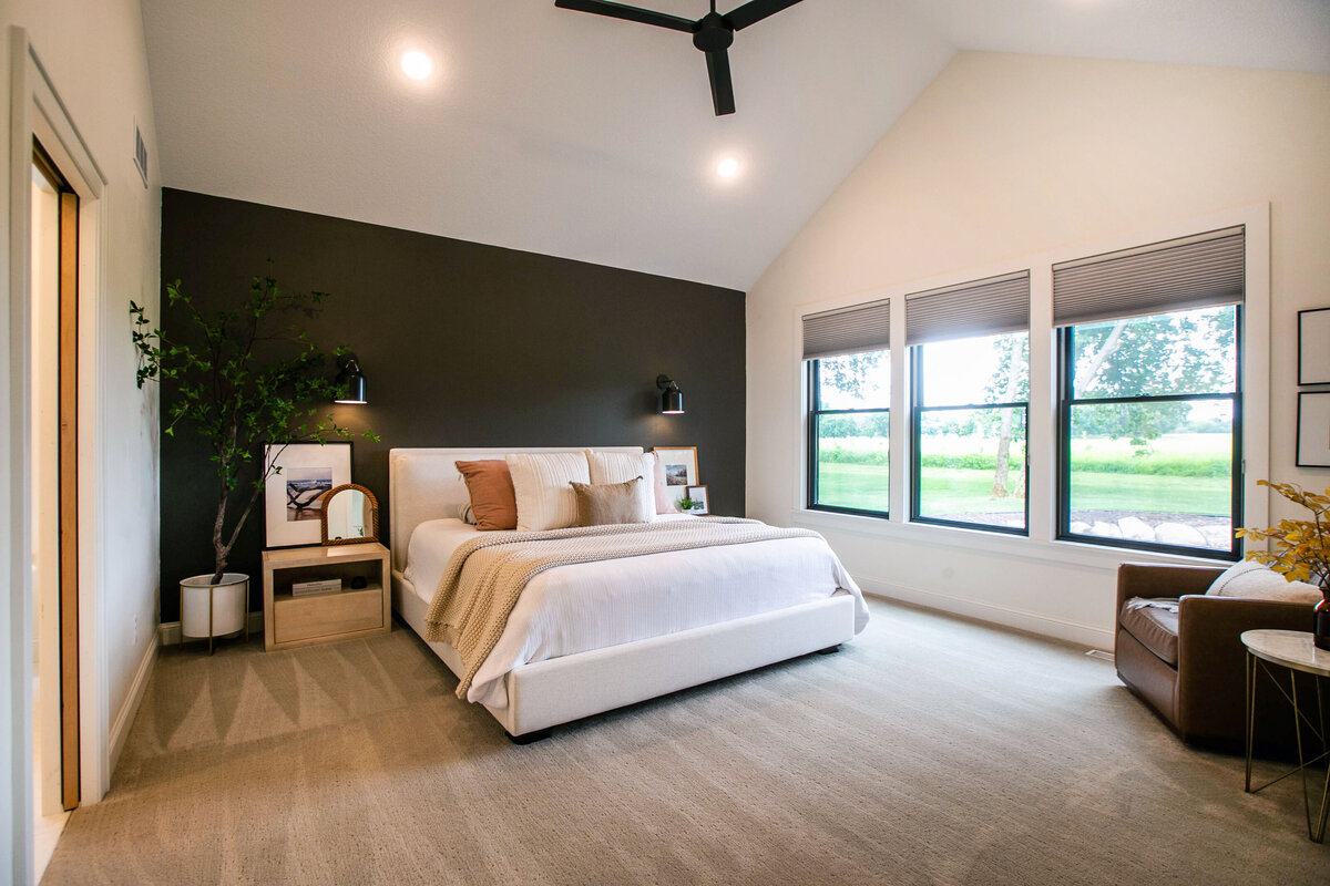 Spacious primary bedroom in custom Otsego home with natural light, wood floors and raised ceiling