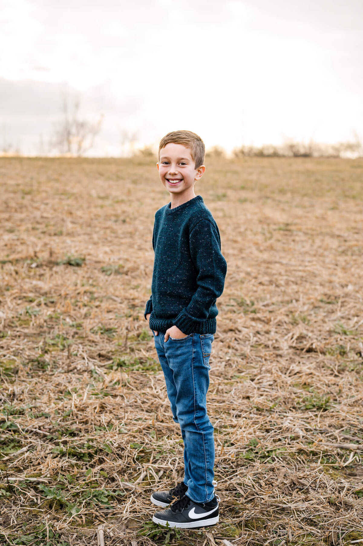 young boy standing with hands in pockets