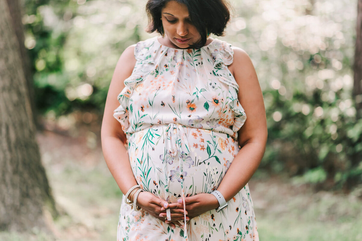 Expecting mama wearing a floral dress, reflecting on becoming a mother, captured by Denise Van Photography