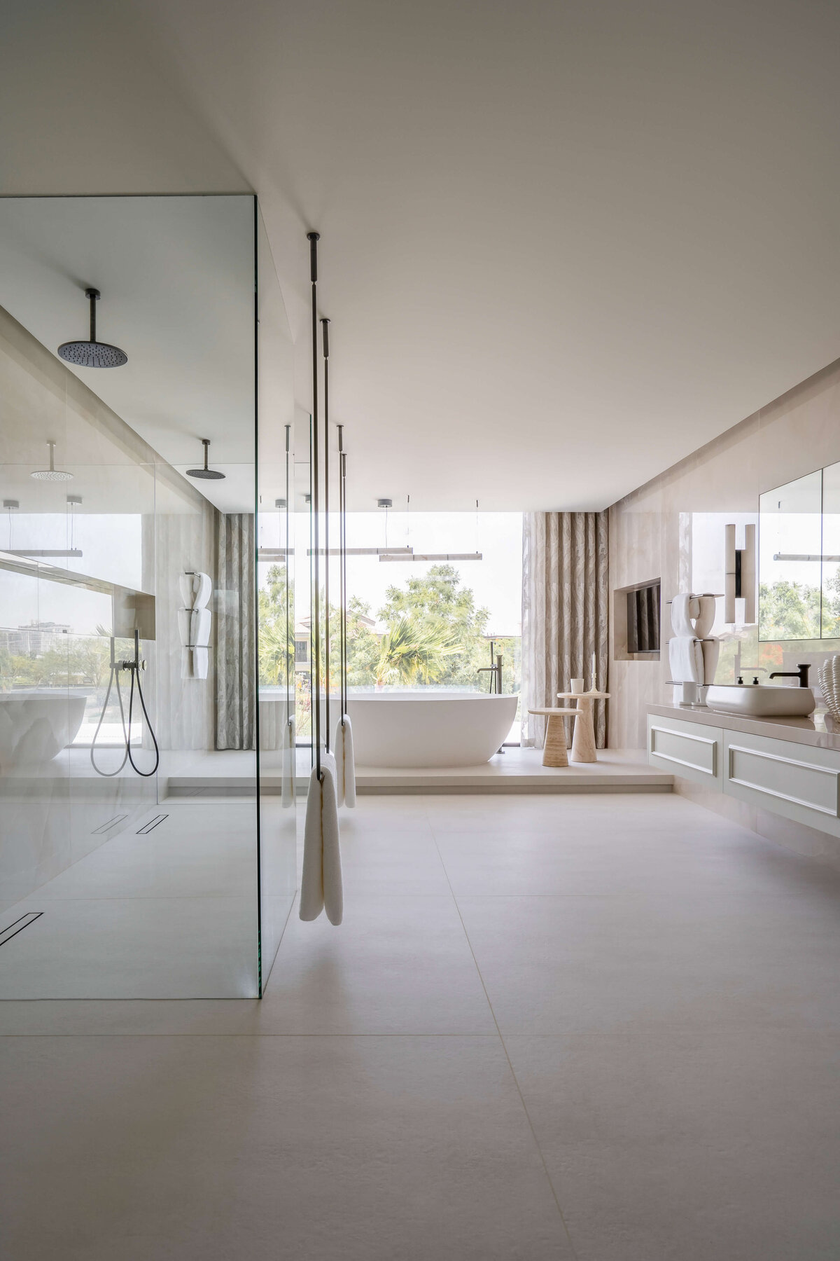 Spacious, modern primary bathroom with a double sink to the right, a large, glass walk-in shower to the right, and a large soaking top against the far wall.