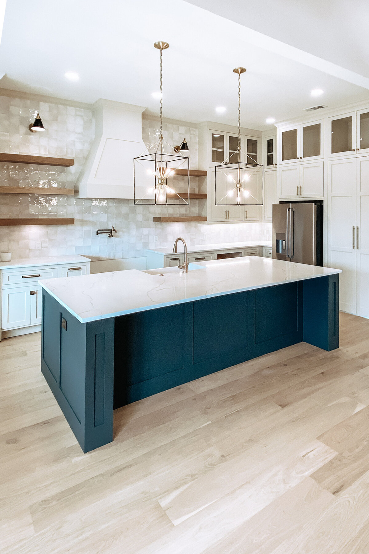 large kitchen island with black and white cabinets, neutral backsplash and light wood flooring