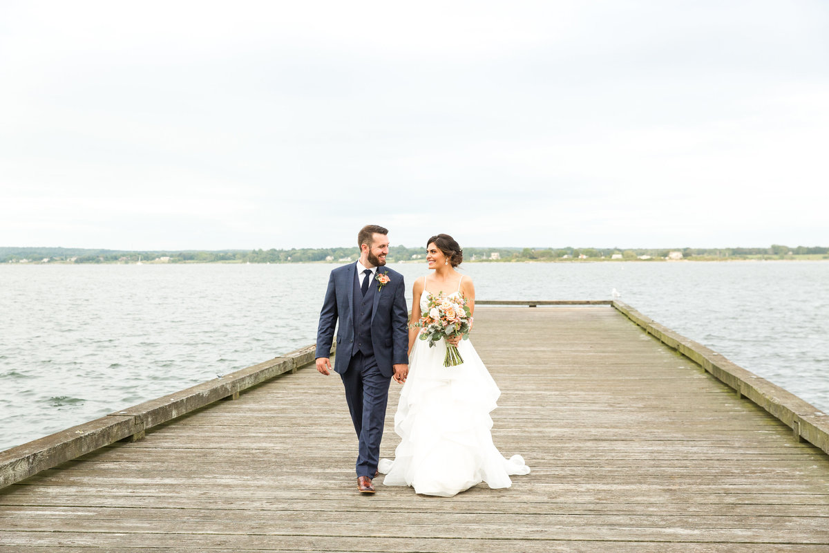 Bride and groom walking down the dock overlooking the Sakonnet