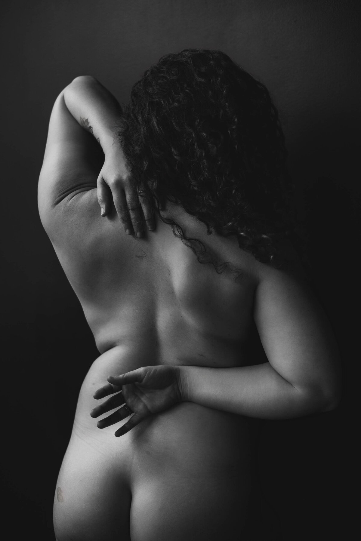 artistic black and white photo of a woman's back during a sstudio boudoir shoot