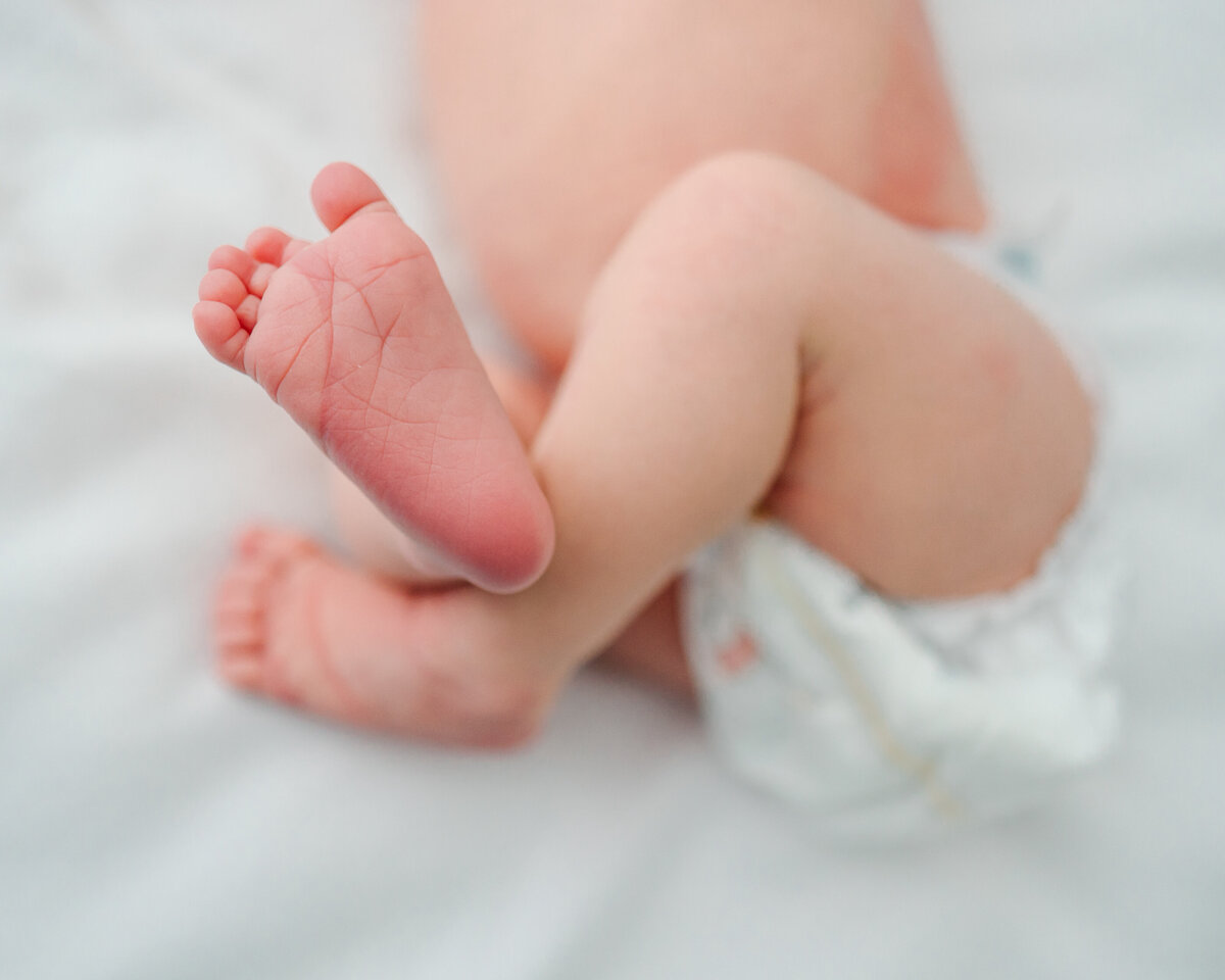 Albuquerque's maternity and newborn photography studio with this adorable close-up image of a newborn's feet in diapers. The photo highlights the delicate features of the baby's tiny feet.