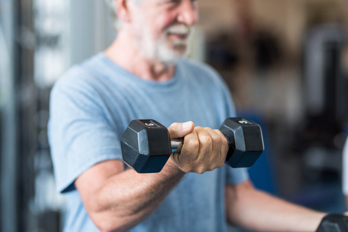 close-up-of-mature-man-holding-two-dumbbells-doing-4SDS8T6