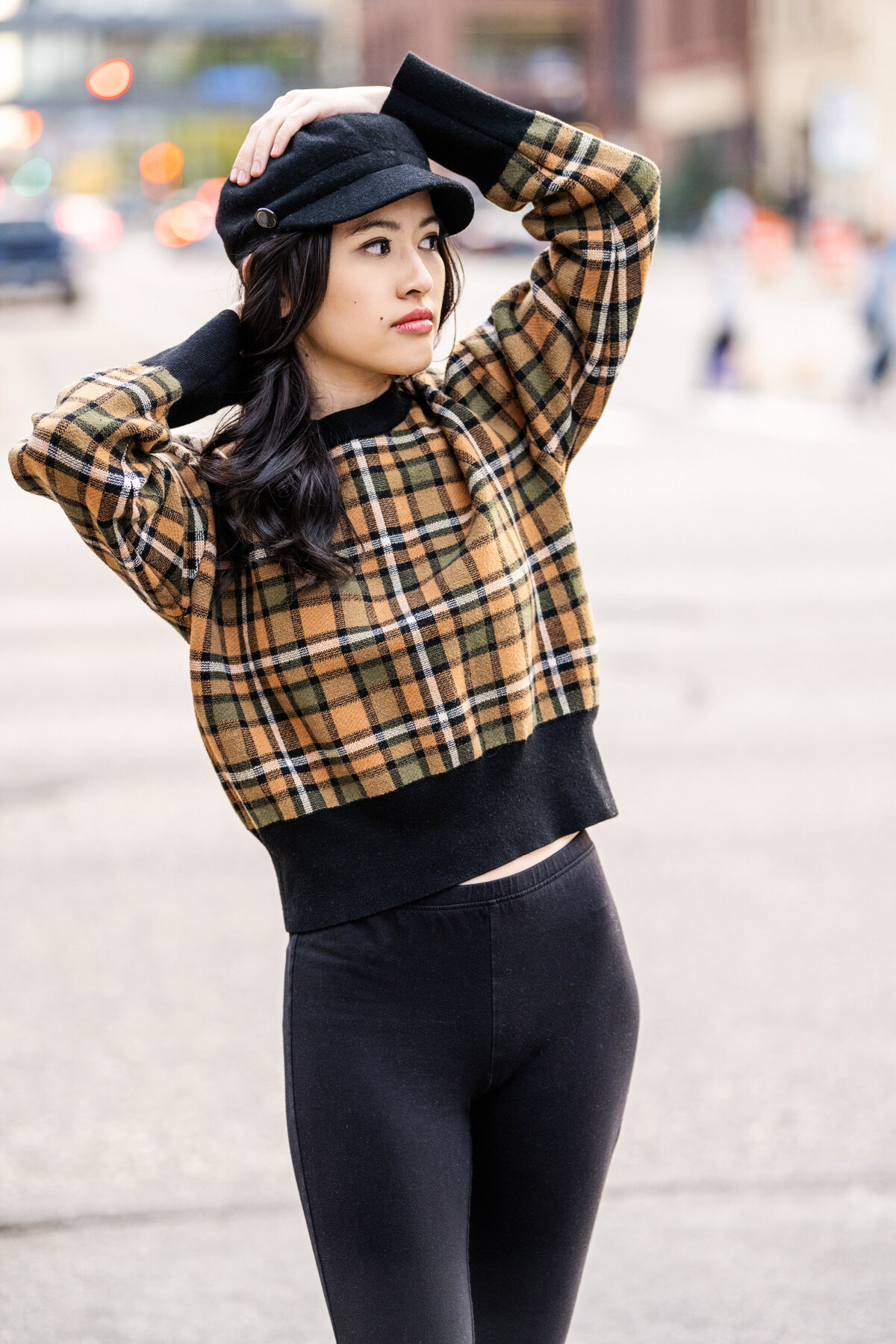 senior photo of girl with plaid sweater and hat in urban street
