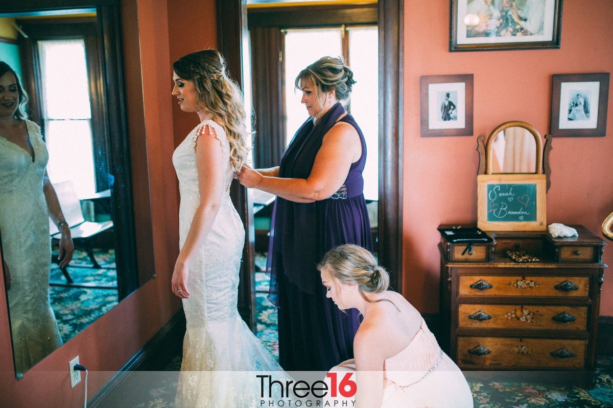 Others help Bride finish getting dressed