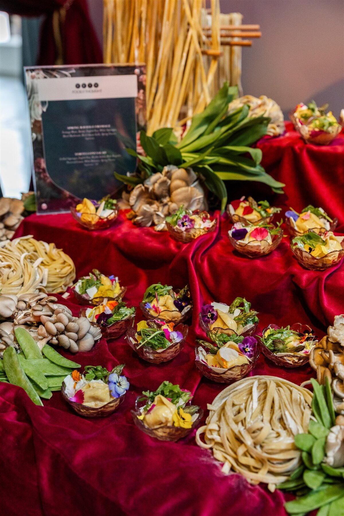 Venue space styled as a fresh pasta station, featuring aesthetic displays of fresh pasta dishes, placed over grand draped tables