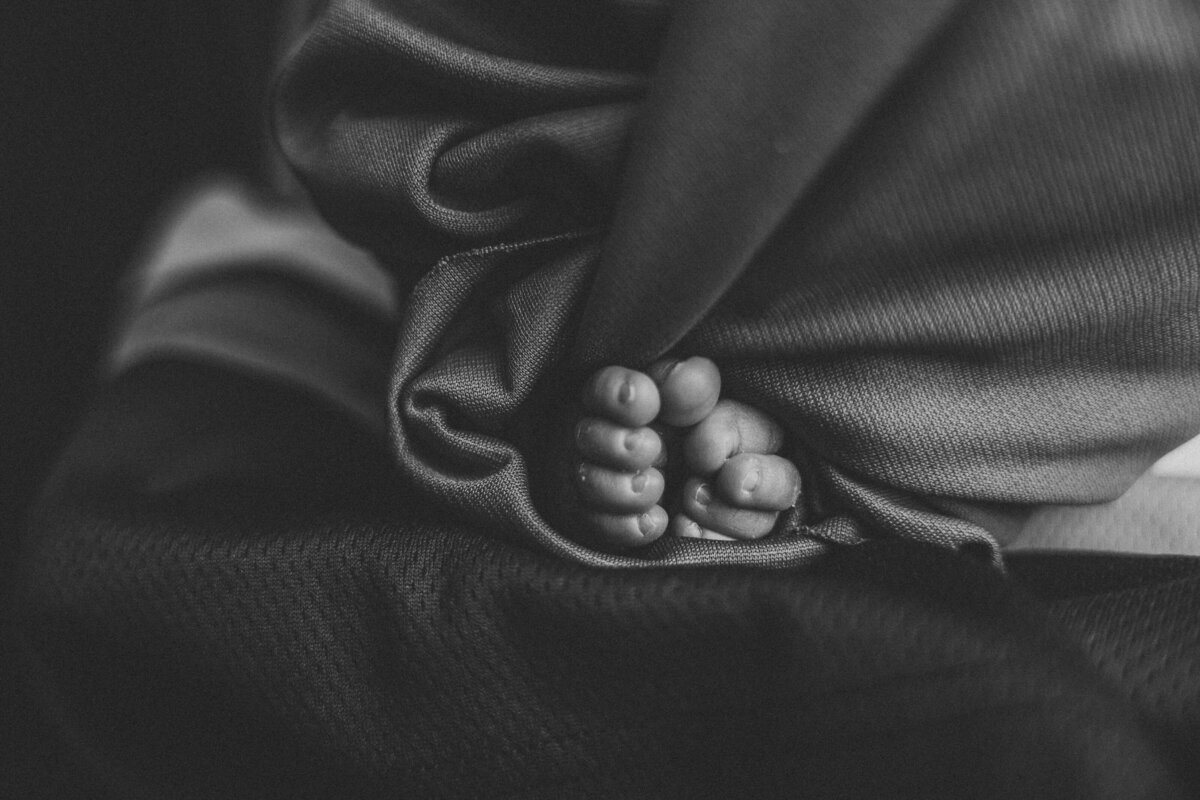 Infant toes peek out of a swaddle.