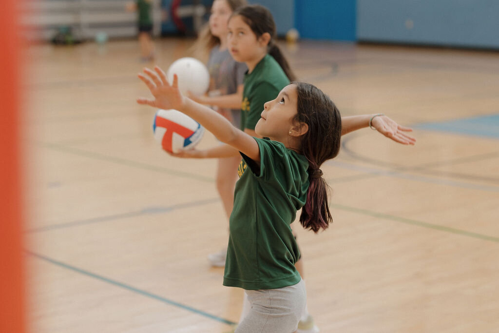 Girl serving volleyball during oceanside, CA pley sports camp