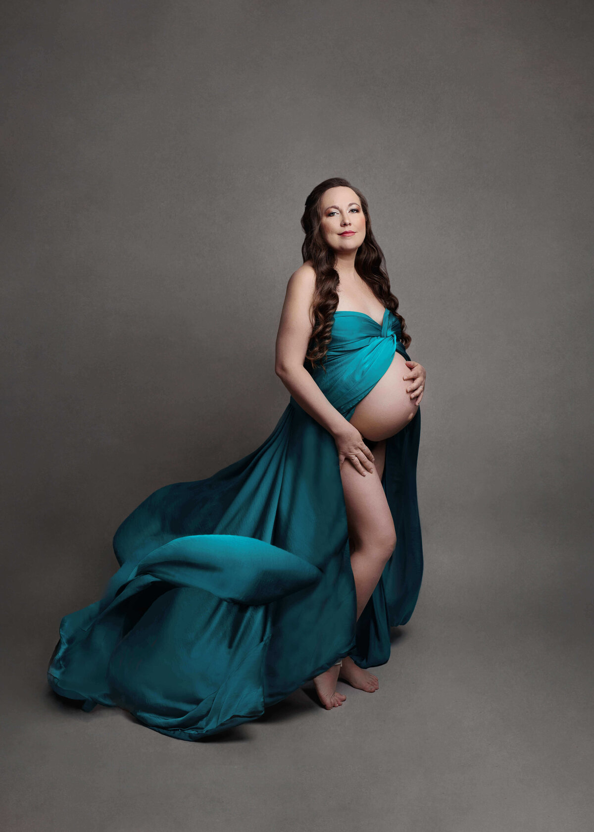 pregnant mother wearing a teal flowey silky  maternity  fabric at her pregnancy session in northern va