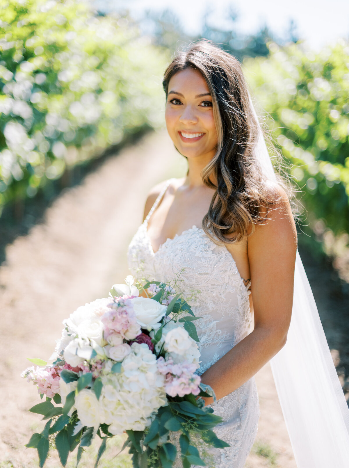 Bride holdinga white with pink flower bouquet.