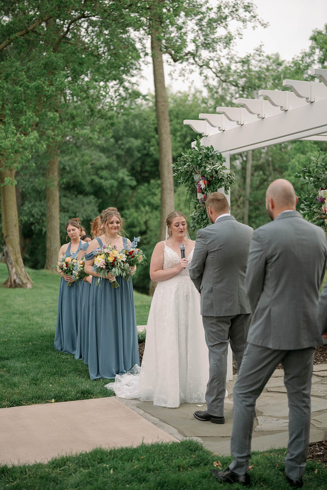 Side view of the bride reading her vows during the outdoor ceremony at The Blue Heron Barn in Kalamazoo Michigan.