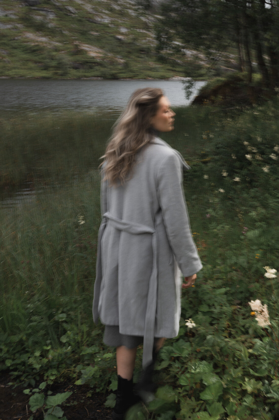 Fashion model walking through the Scandinavian landscape in grey coat