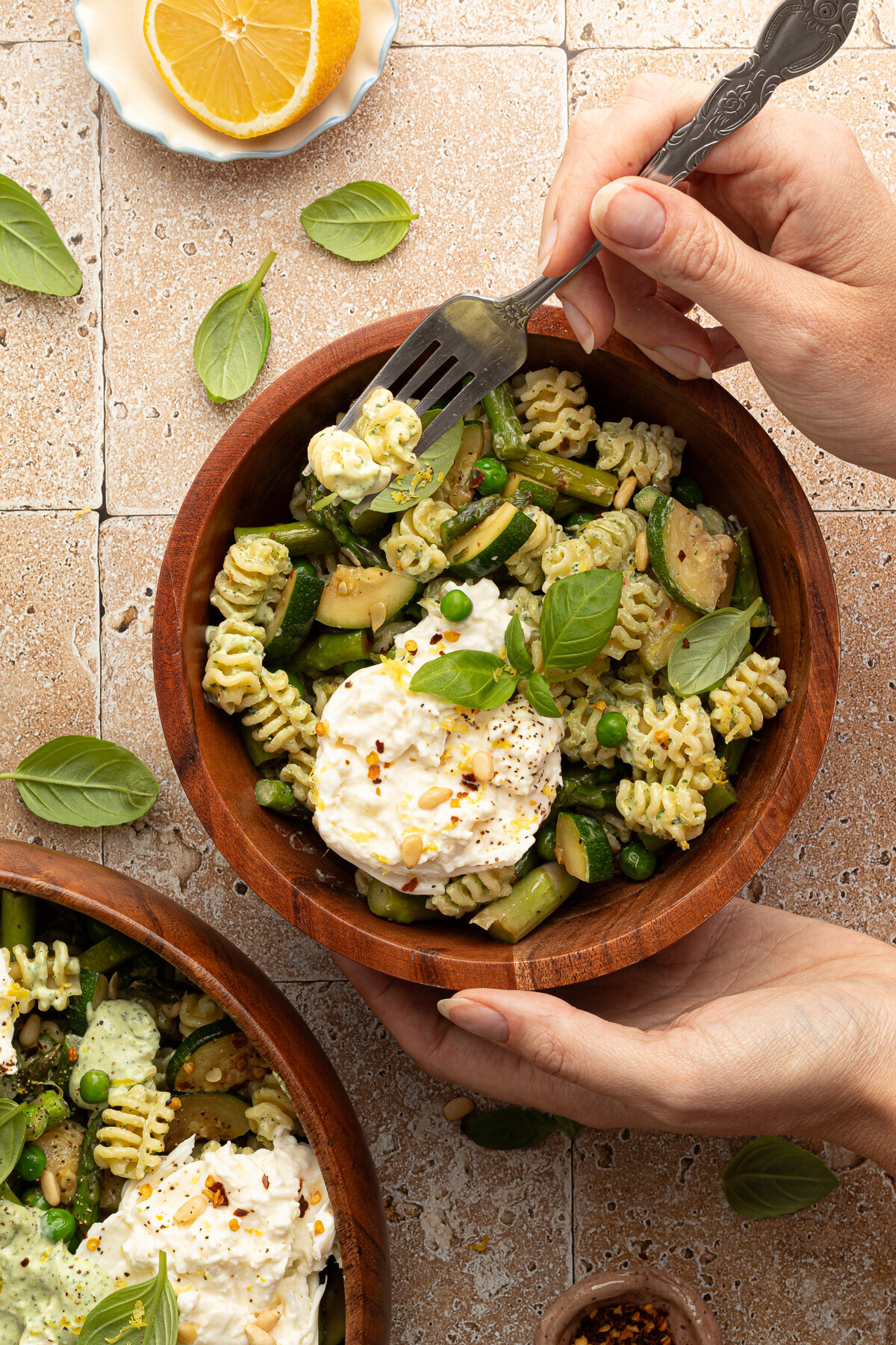 hands putting a fork into a bowl of pasta salad