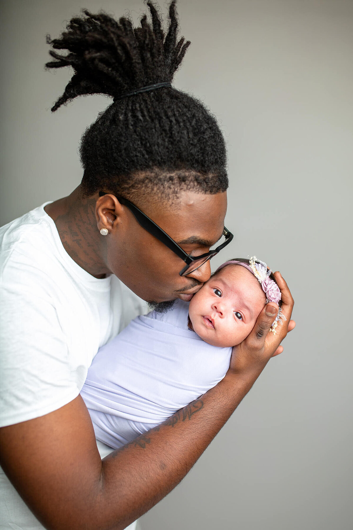 Dad kissing newborn baby on cheek 