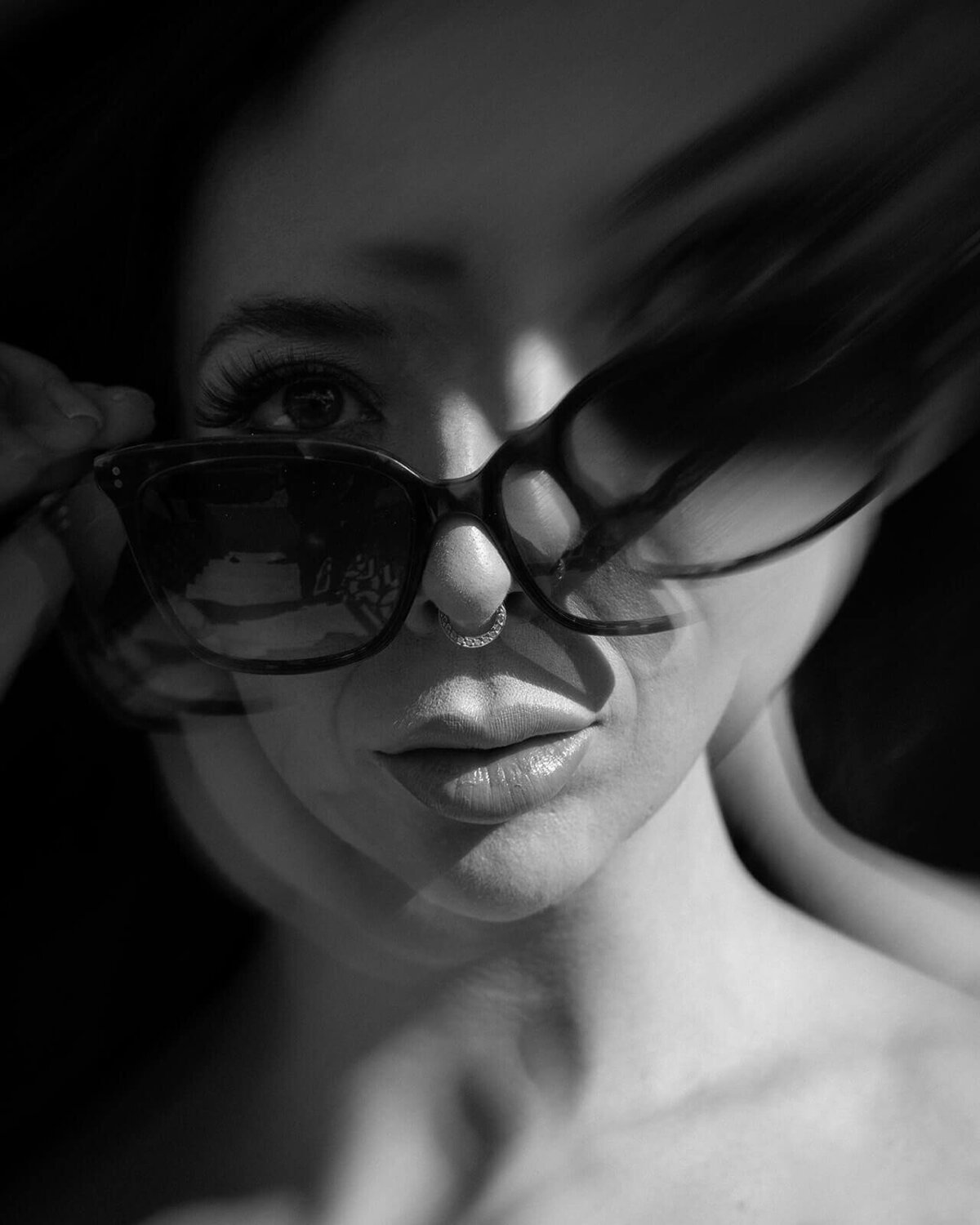 Bride poses artistically in sunglasses, the lens creates a dramatic movement effect.