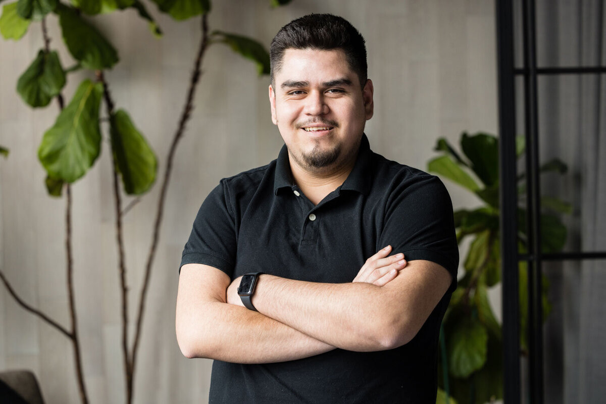 Smiling man with arms crossed wearing a black polo shirt